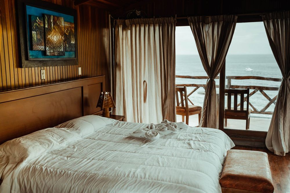 Spacious bedroom with a large bed and a balcony door open to the sea