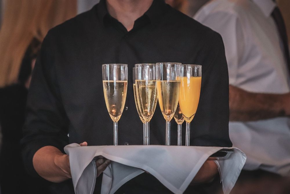 Server holding a tray of champagne and orange juice glasses