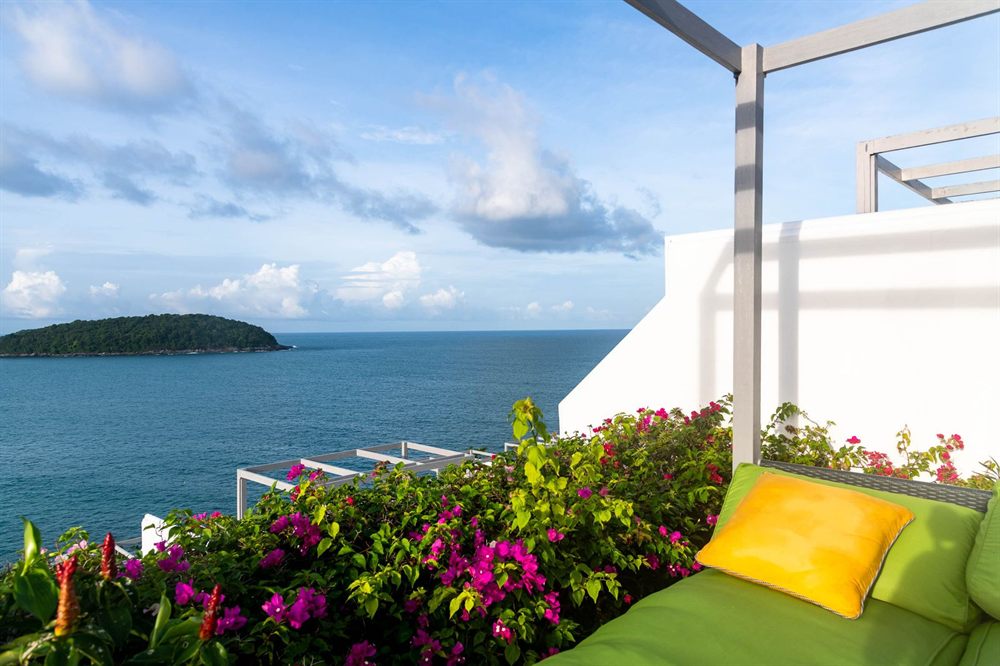 Balcony with cushions and flowers above a calm blue sea